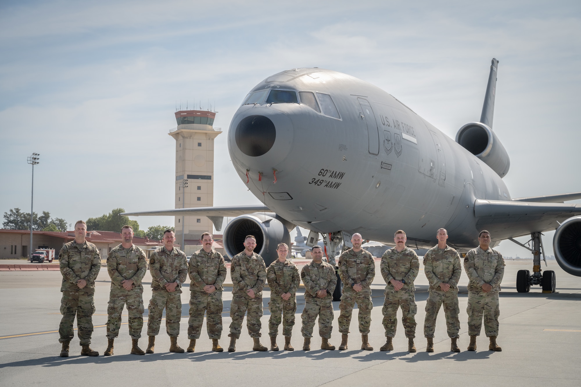 11 Airmen stand in front of a military aircraft for a photo