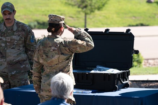  U.S. Air Force Senior Airman Savannah Serda, 50th Force Support Squadron, salutes after putting an Air Force flag in the Team Schriever time capsule next to U.S. Air Force Master Sgt. James Carroll, First Sergeant of Schriever Mission Support Directorate,   on Schriever Space Force Base on June 21, 2023. The flag was the final Air Force flag flown on the base and was placed in the time capsule as a symbolic remembrance of the men and women who served this base. (U.S. Space Force photo by Airman 1st Class Justin Todd)