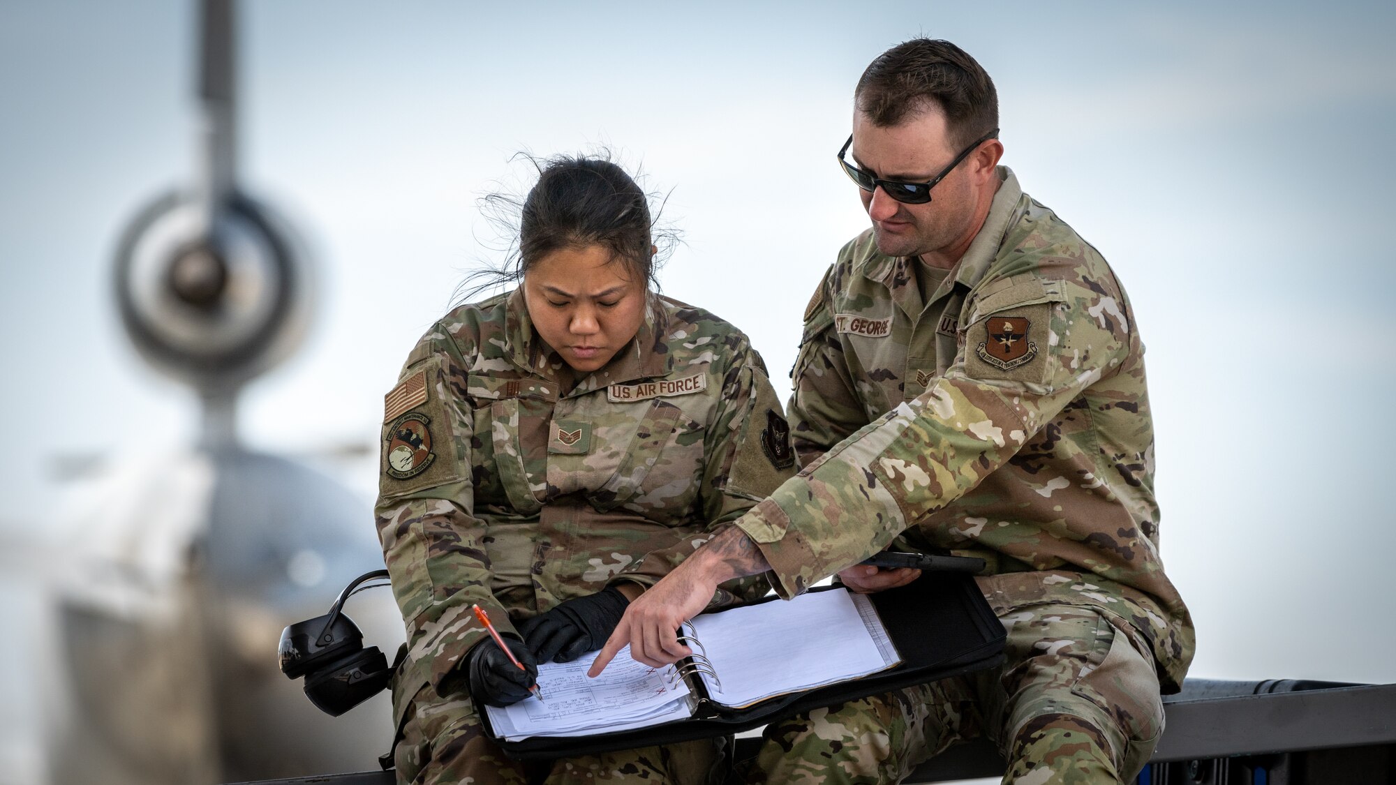 An Airman points to a page in a book for another airman