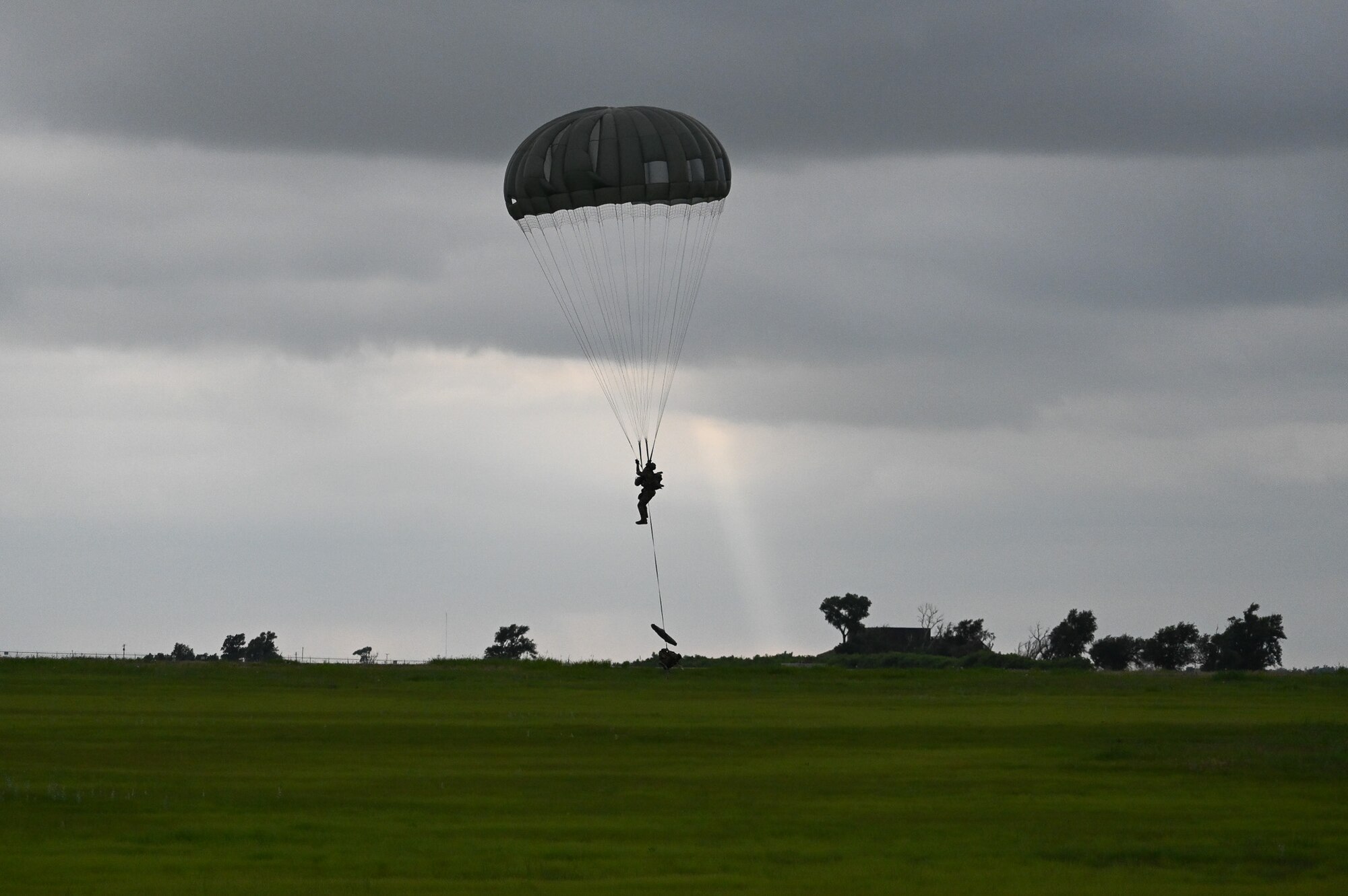 A U.S. Air Force 824th Base Defense Squadron (BDS) fire team member parachutes out of a 910th Airlift Wing C-130 Hercules, June 13, 2023, at Clinton Sherman Airport, Oklahoma. The BDS drop exercised security forces and 7th Air Support Operations Squadron (ASOS) Tactical Air Control Party (TACP) ability to remain agile in changing conditions in support of Exercise AGILE BLIZZARD-UNIFIED VISION. (U.S. Air Force photo by 2nd Lt. Steven Smith)