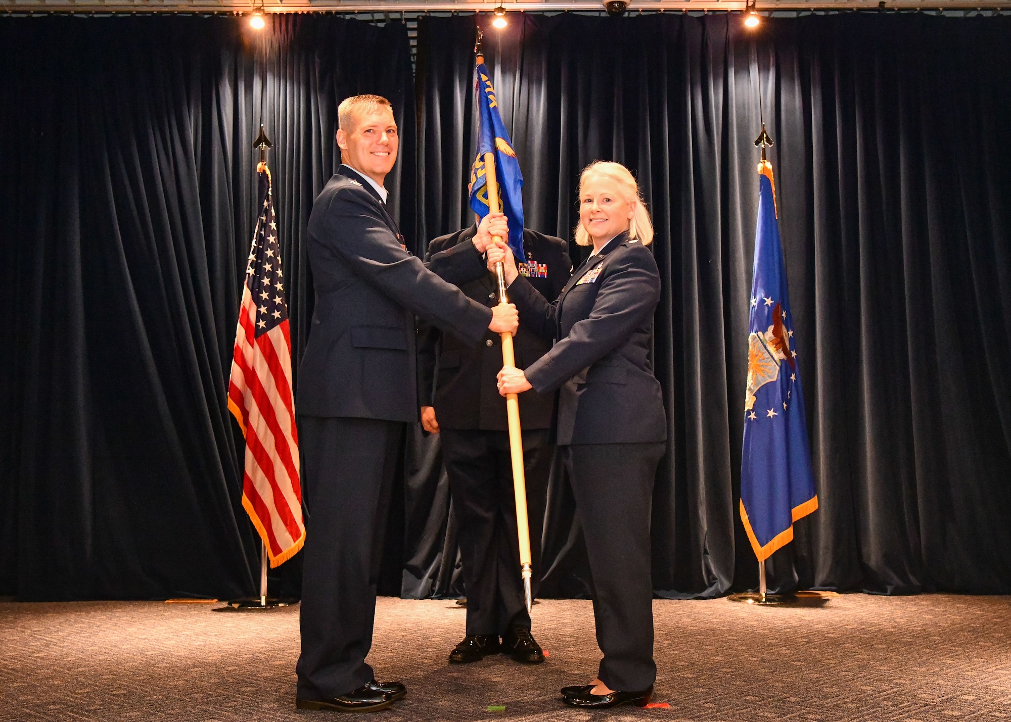 Col. Brad Brough (left), 374th Medical Group commander, hands a squadron guidon to Lt. Col. Jaime F. Kelbaugh, signifying her appointment as the new commander of the 374th Surgical Operations Squadron, during an assumption of command ceremony