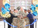 Group of people cutting blue ribbon.