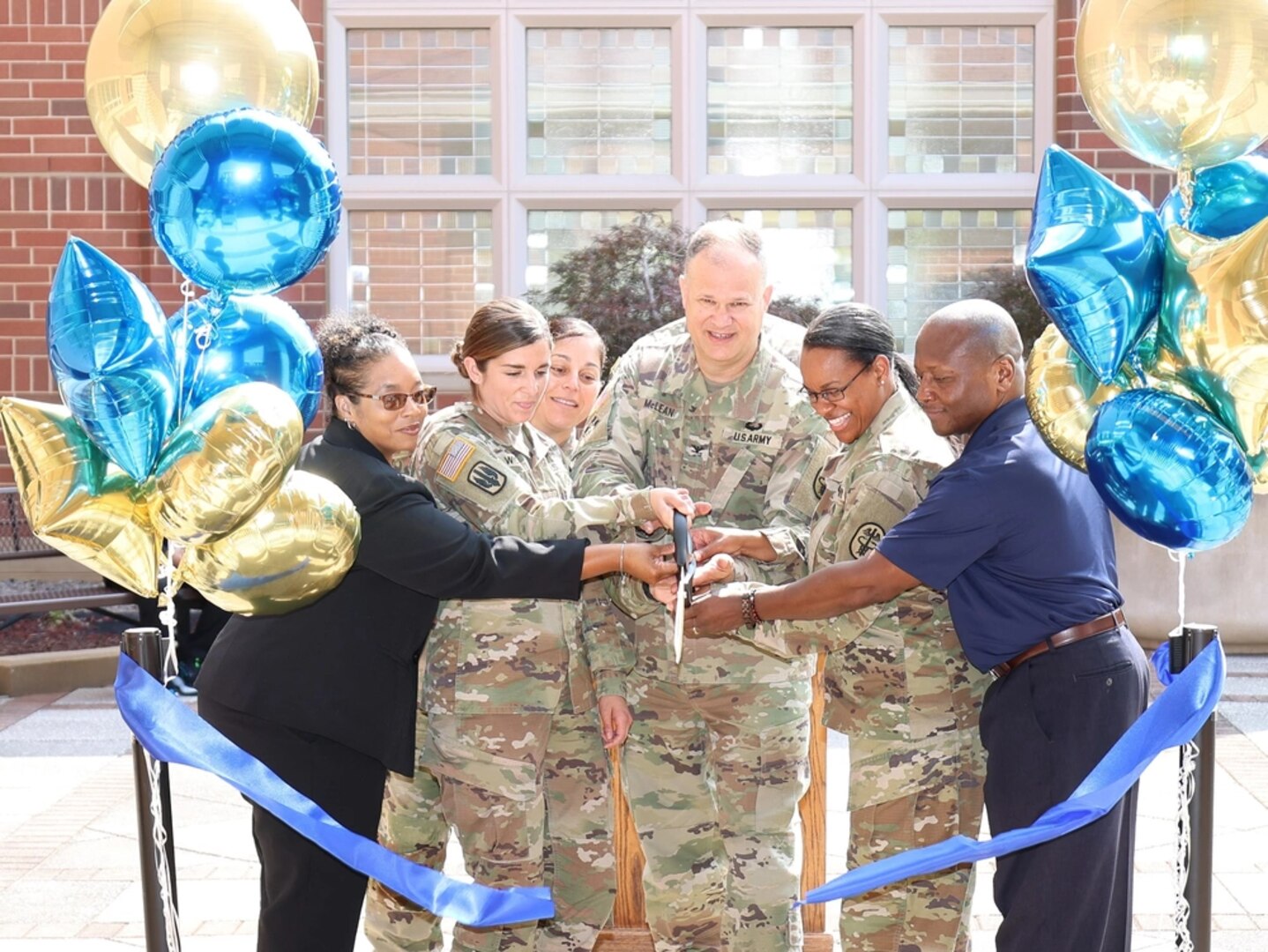 Group of people cutting blue ribbon.