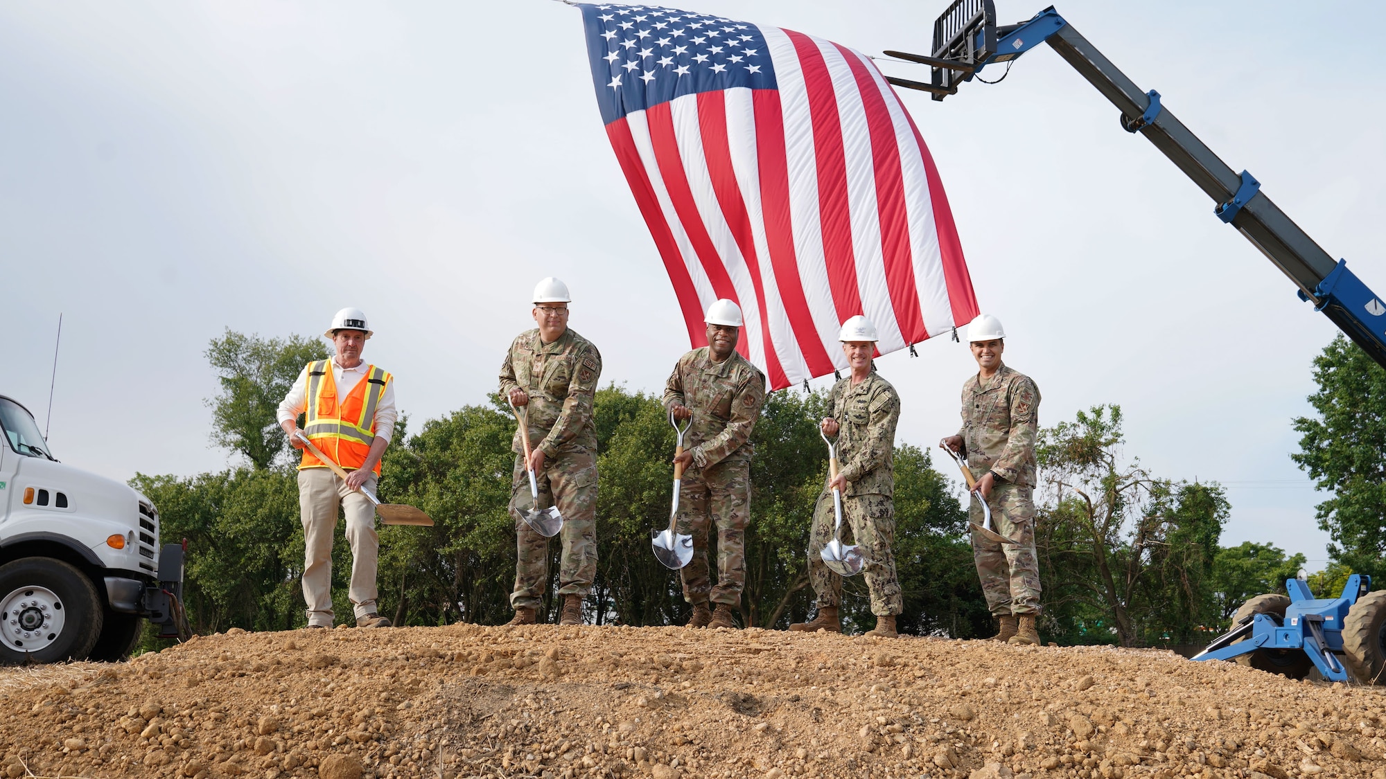 Five men dig into ground, symbolizing the beginning of a new construction project.