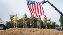 Five men dig into ground, symbolizing the beginning of a new construction project.