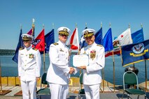 Rear Adm. Mark Sucato, commander, Navy Region Northwest, presents a meritorious service medal to Cmdr. Andrew Crouse during a Naval Magazine (NAVMAG) Indian Island change of command ceremony that took place on the ammunition pier in Port Hadlock, Washington, June 22, 2023. During the ceremony, Cmdr. Andrew Crouse was relieved as commander of NAVMAG Indian Island while Cmdr. Todd Galvin assumed his position as the incoming commanding officer. (U.S. Navy photo by Mass Communication Specialist 2nd Class Gwendelyn L. Ohrazda)