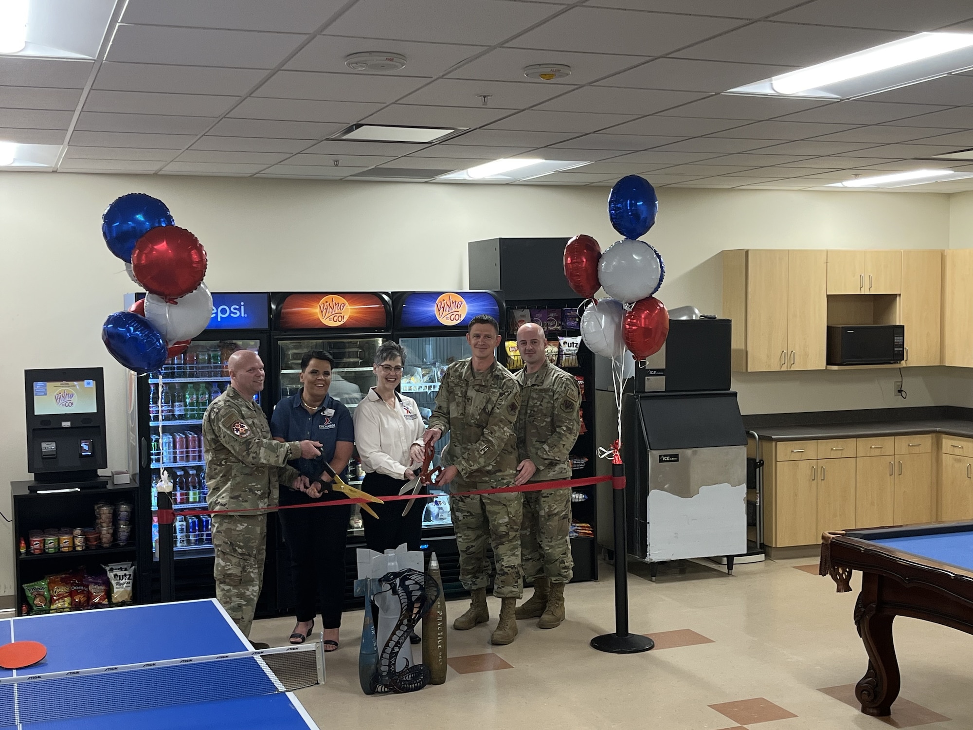 five people stand in front of a blue ribbon