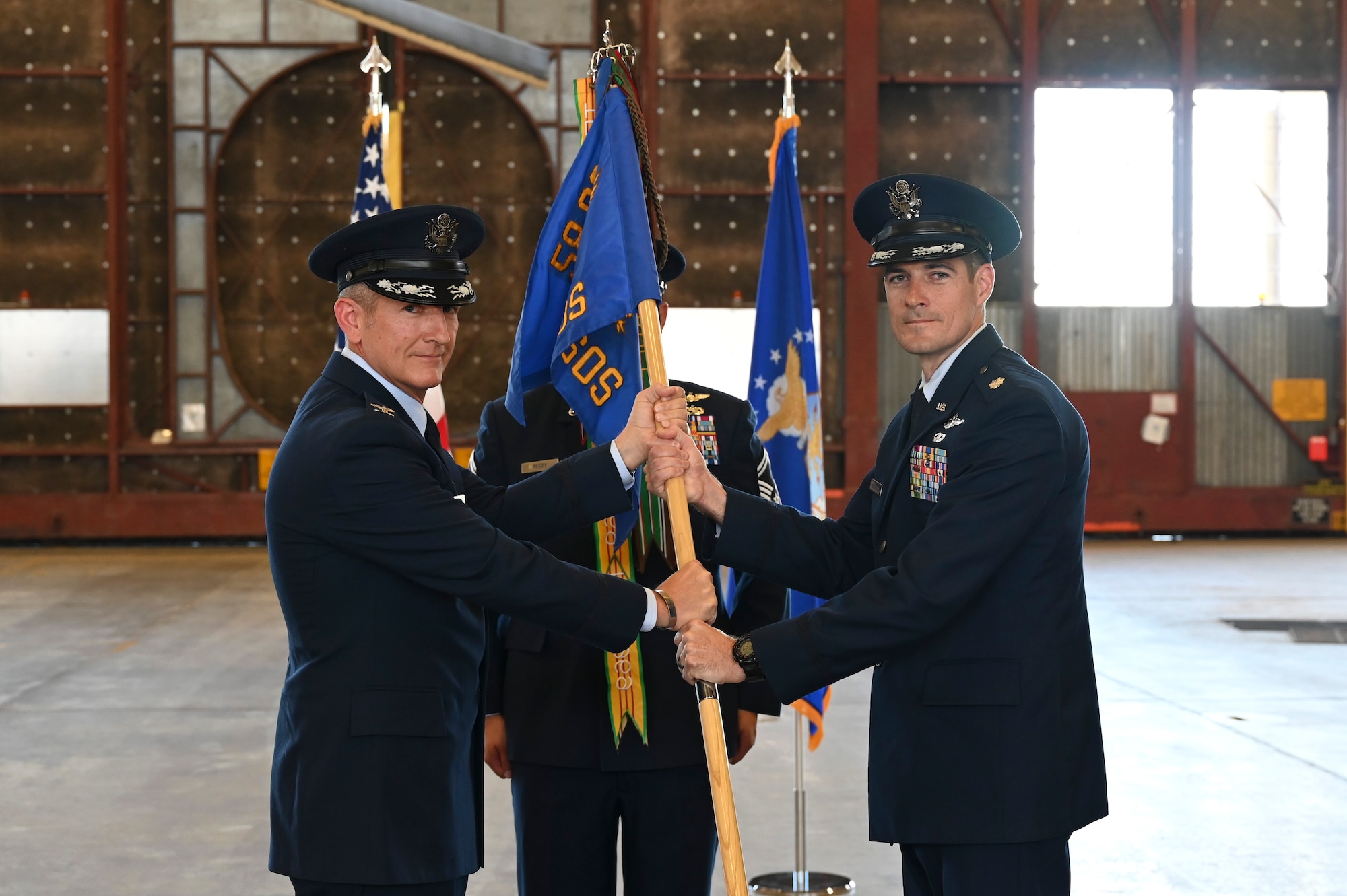 A man passes a guidon to a man.