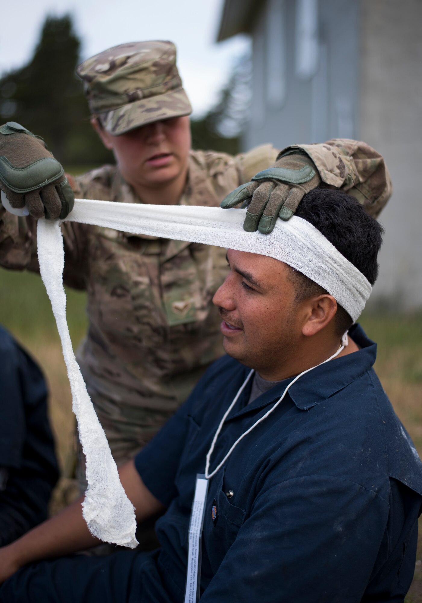 Oregon Air National Guard Senior Airman Margo Testa, 142nd Medical Group, applies a bandage to the head of a moulaged victim during a Pathfinder exercise at Camp Rilea, Warrenton, Ore., June 14, 2019. Pathfinder is an interagency disaster response event designed to assess and enhance military and civilian response capabilities in the event of a Cascadia subduction zone catastrophe in the Pacific Nothwest region. (U.S. Air National Guard photo by Tech. Sgt. Steph Sawyer, 142nd Fighter Wing Public Affairs)