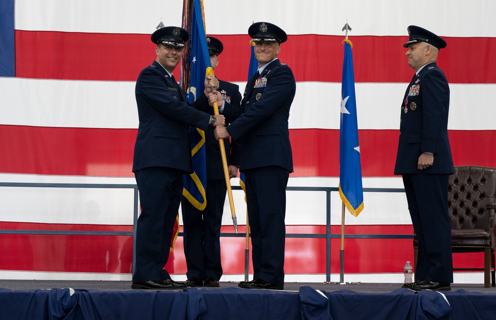 U.S. Air Force Maj. Gen. Andrew J. Gebara, Eighth Air Force and Joint-Global Strike Operations Center commander, left, presents the 28th Bomb Wing guidon to Col. Derek C. Oakley, incoming 28th BW commander, center, during a change of command ceremony at Ellsworth Air Force Base, South Dakota, June 23, 2023.