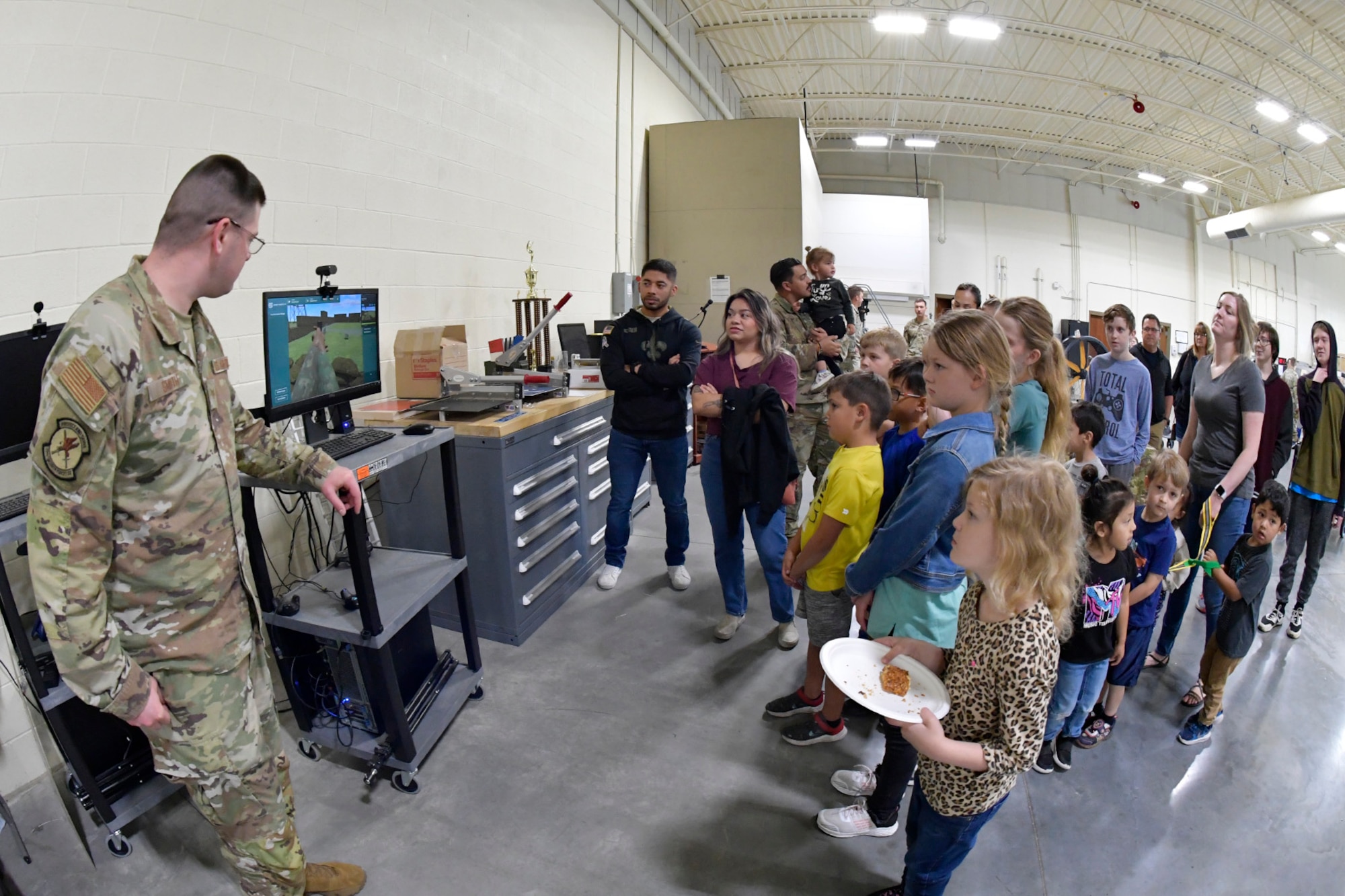 (Left) Staff Sgt. Ronald Smith, 75th Security Forces Squadron, demonstrates a virtual reality training simulator during 75th SFS Spouses Day June 15, 2023, at Hill Air Force Base, Utah. This event was held to give family guests a closer look into how the squadron operates on a day-to-day basis and is aimed at further developing a sense of inclusion among the spouses and their families. (U.S. Air Force photo by Todd Cromar)