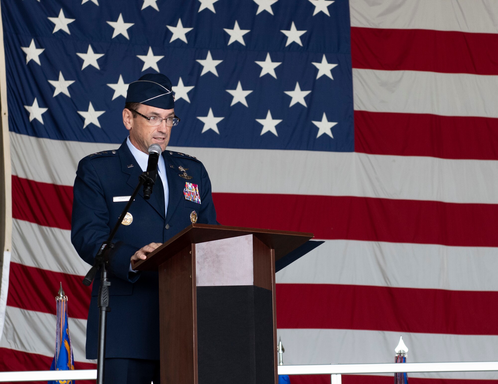 A man speaks at a podium in front of an American flag