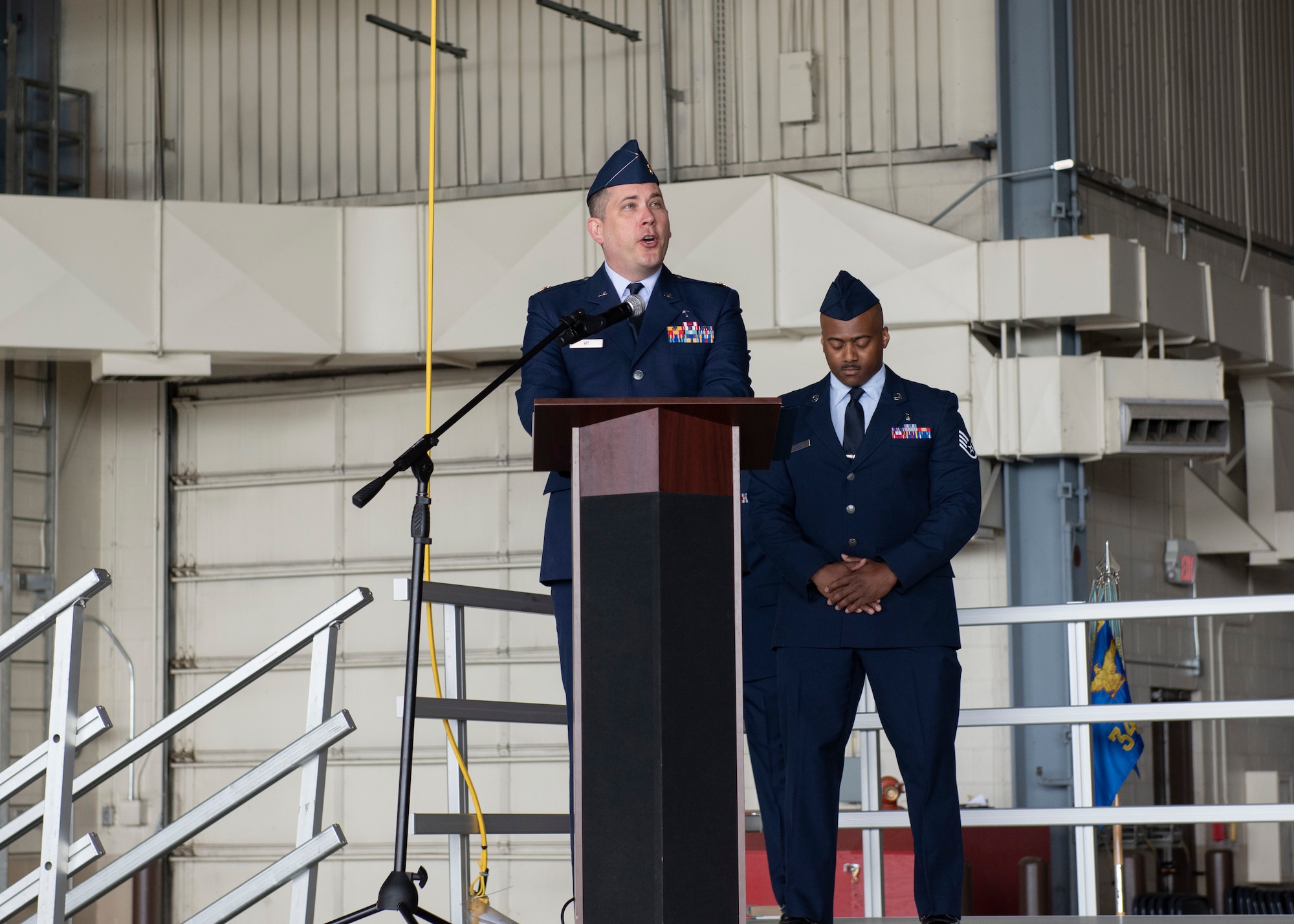 A man in a blue uniform speaks at a podium.