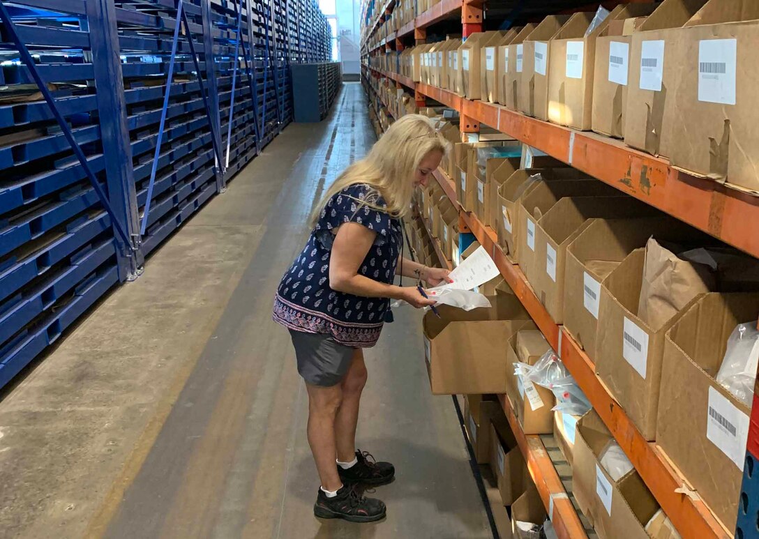 Christina Meighan looking at paperwork in a warehouse.