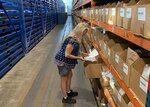 Christina Meighan looking at paperwork in a warehouse.