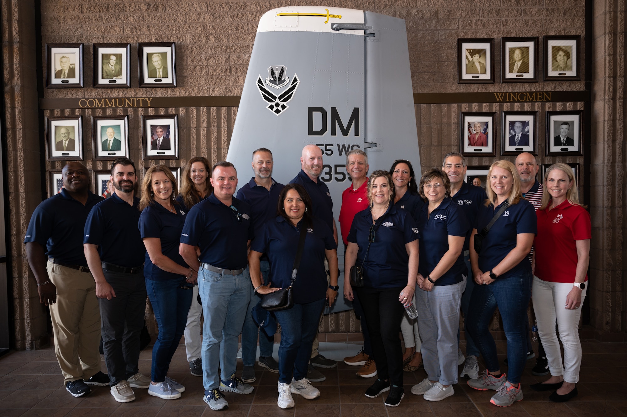 USAA senior executives pose for a group photo in front of a detached aircraft wing in the wing building at Davis-Monthan Air Force Base, Ariz., June 22, 2023. The executives received the opportunity to tour DM and learn about our Airmen. (U.S. Air Force photo by Airman 1st Class Jasmyne Bridgers-Matos)