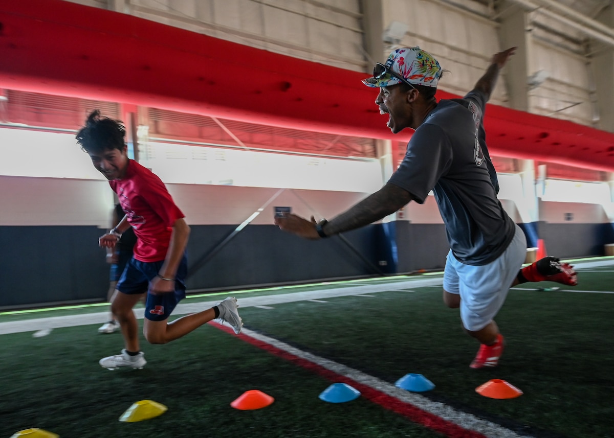 A photo of a man chasing a child during a football drill.