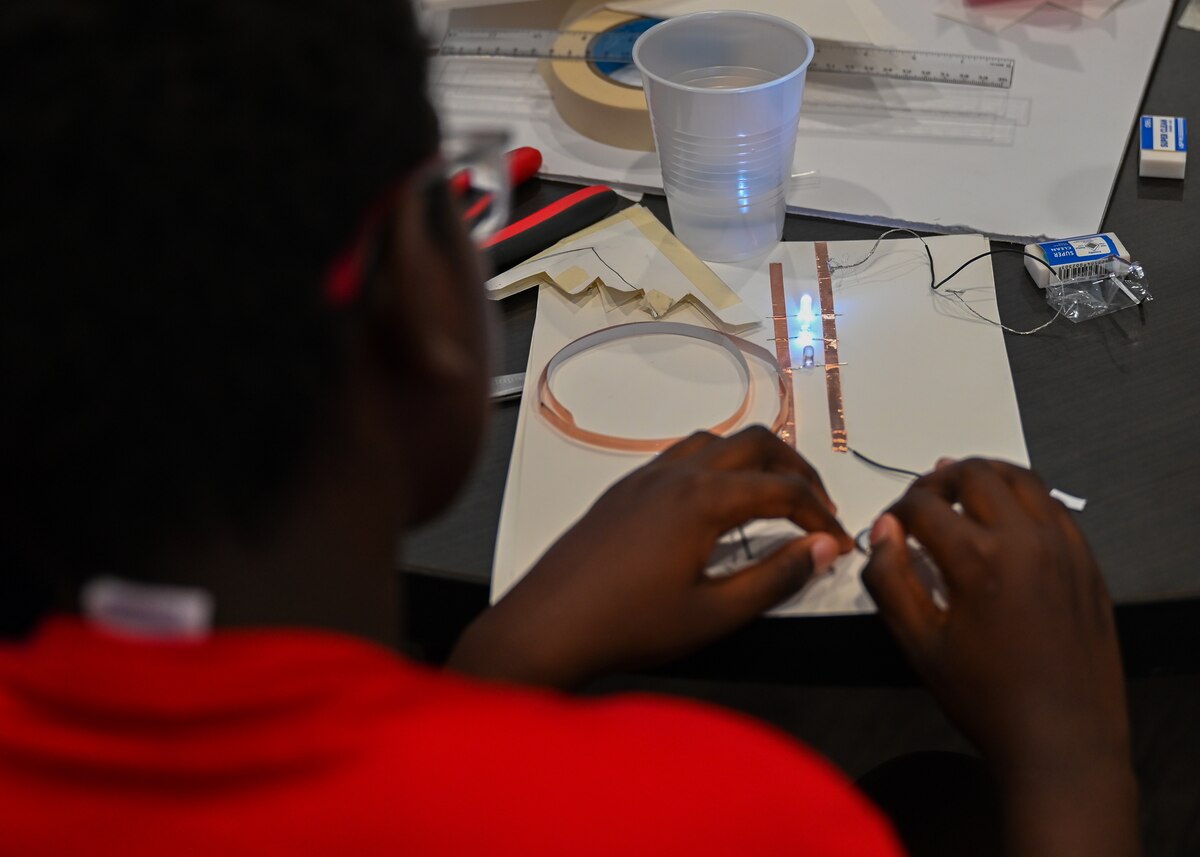 A photo of a child using a small battery to power lights.