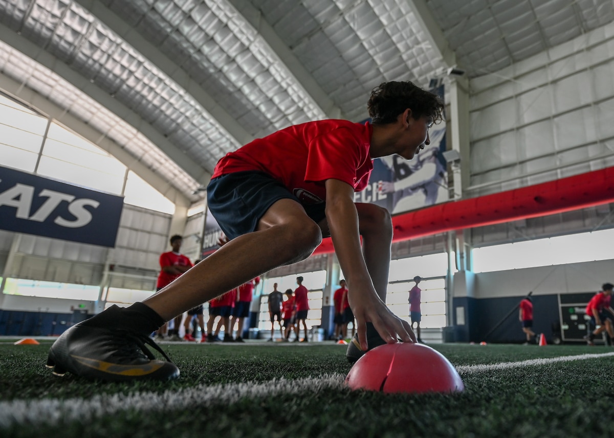 A photo of a child touching a cone during a football drill.