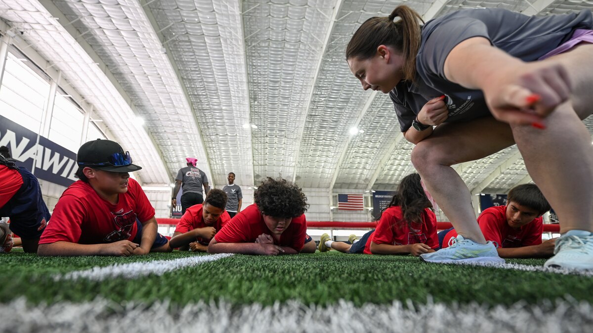 A photo of a group of children low crawling on a football field.