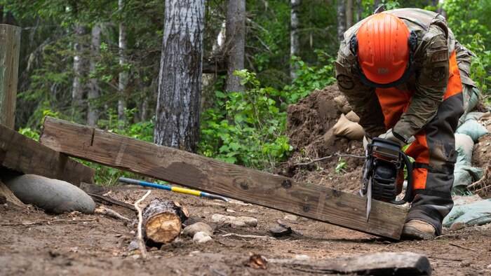 U.S. Air Force Airman 1st Class Joshua McGuire, 773d Civil Engineer Squadron, cuts a beam of wood at Camp Mad Bull at Joint Base Elmendorf-Richardson, Alaska.