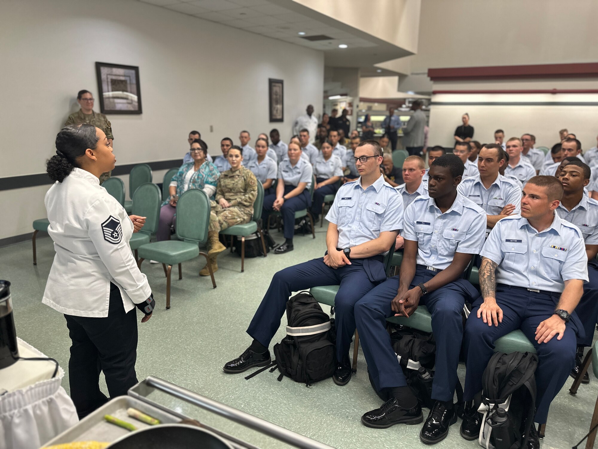 Master Sgt. Opal Poullard, 345th Training Squadron, talks to Security Forces Technical School students at a cooking demonstration at JBSA-Lackland, Texas, June 15, 2023. Poullard, who’s an Advanced Culinary Instructor for the Joint Culinary Center of Excellence, was on base to support healthy living events through the Robert Irvine Foundation’s Breaking Bread with Heroes Program. Poullard, spent 14 years as a Defender before she retrained into a special duty career field and became an Enlisted Aide. Poullard was the winner of the Military Salute Edition of the Food Network show, Chopped. (U.S. Air Force photo by Daniel Cruz)