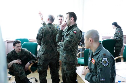Majs Timmy Wang and Noah Mulholland discuss enemy most likely and enemy most dangerous courses of action with their Polish colleagues in preparation for course of action wargaming.