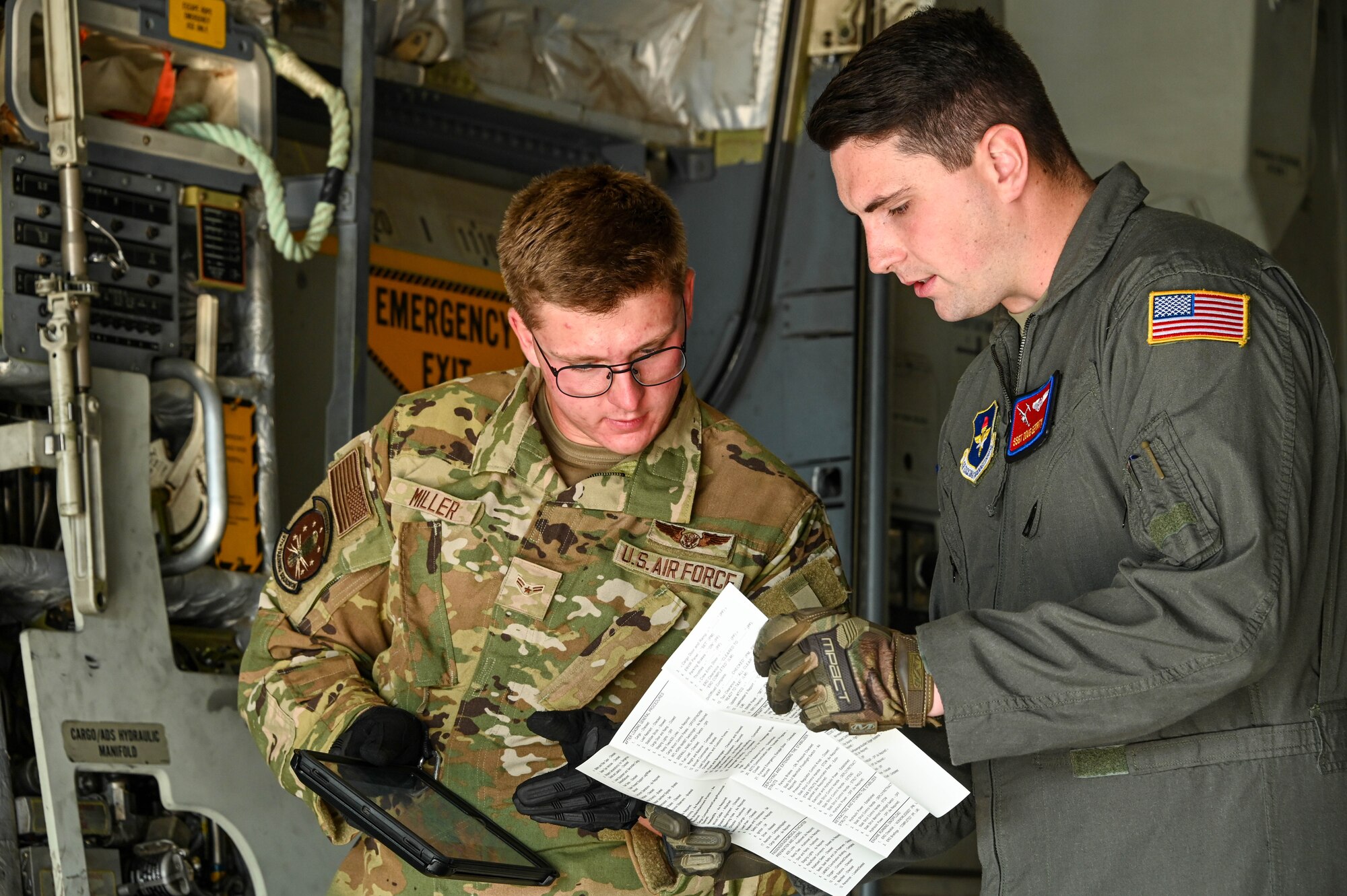 U.S. Air Force Staff Sgt. Douglas Gerrity (right), 58th Airlift Squadron loadmaster instructor, trains Airman 1st Class Donald Miller (left), 97th Training Squadron student, on the next steps after opening the cargo door of a C-17 Globemaster III at Altus Air Force Base, Oklahoma, June 23, 2023. Gerrity recently reenlisted for four more years in the Air Force to continue his education in health science. (U.S. Air Force photo by Senior Airman Kayla Christenson)