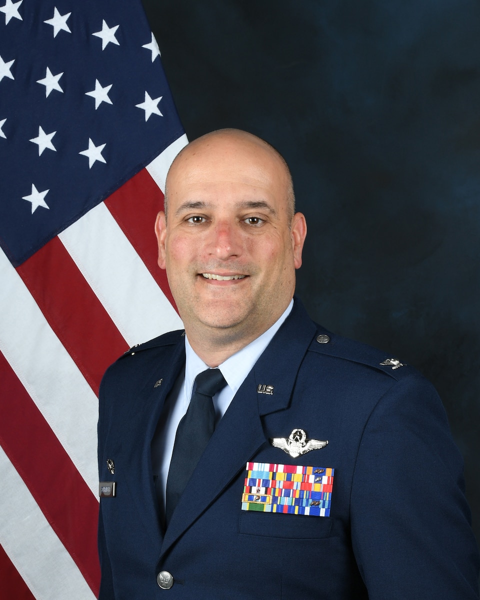 photo of uniformed US military member with a US flag in the background