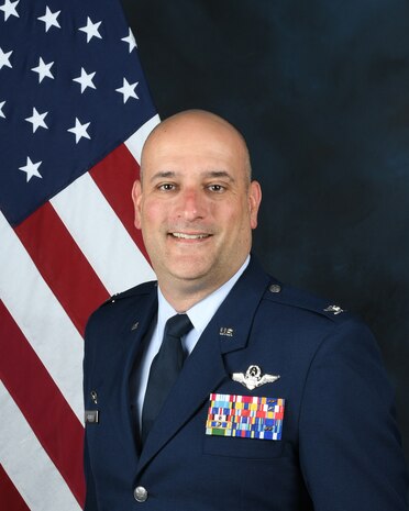 photo of uniformed US military member with a US flag in the background