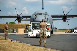 Airmen from the 123rd Airlift Wing, Kentucky National Guard, marshal a German aircraft tug towing a C-130J Super Hercules at Wunstorf Air Base, Wunstorf, Germany, June 12, 2023.  Exercise Air Defender integrates both U.S. and allied air-power to defend shared values, while leveraging and strengthening vital partnerships to deter aggression around the world. (U.S. Air National Guard photo by Master Sgt. Phil Speck)