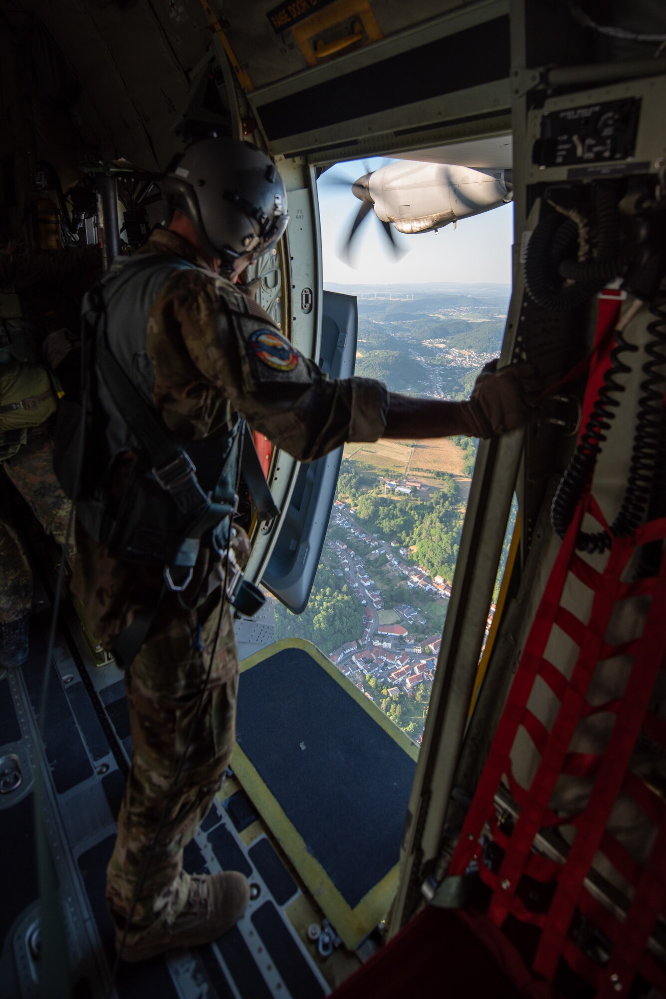 Master Sgt. Chris Kinberger, a loadmaster assigned to the Kentucky Air National Guard’s 165th Airlift Squadron, looks out a paratroop door of a 123rd Airlift Wing C-130J Super Hercules during exercise Air Defender 2023 in Saarbrucken, Germany, June 15, 2023. AD23 integrates both U.S. and allied air-power to defend shared values, while leveraging and strengthening vital partnerships to deter aggression around the world. (U.S. Air National Guard photo by Master Sgt. Phil Speck)