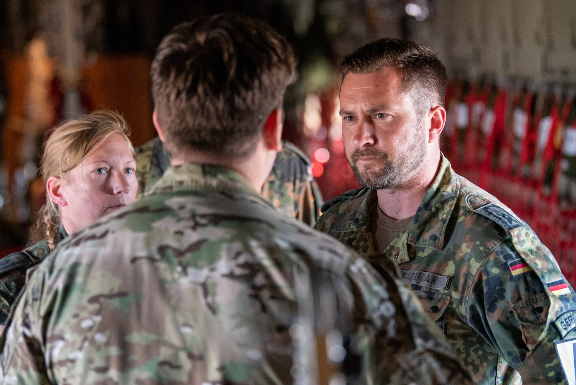 A U.S. Air Force tactical air control party Airman talks with German Armed Forces jumpmasters during exercise Air Defender 2023 in Saarbrucken, Germany, June 15, 2023. AD23 integrates both U.S. and allied air-power to defend shared values, while leveraging and strengthening vital partnerships to deter aggression around the world. (U.S. Air National Guard photo by Master Sgt. Phil Speck)