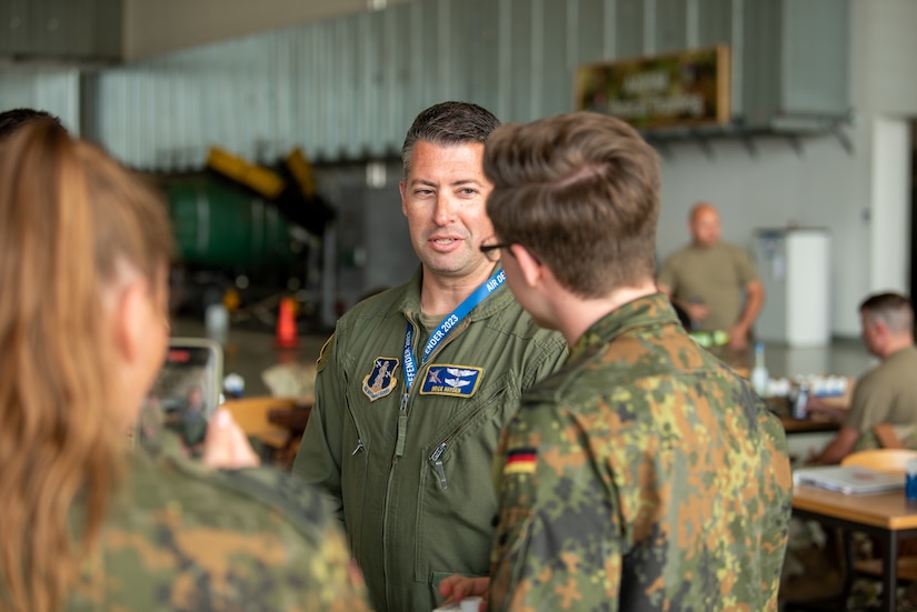 U.S. Air Force Major Brice Hayden, a pilot assigned to the 165th Airlift Squadron, 123rd Airlift Wing, Kentucky National Guard, speaks with German public affairs members at Wunstorf Air Base during exercise Air Defender 2023 (AD23) in Wunstorf, Germany, June 21, 2023. Exercise AD23 integrates both U.S. and allied air-power to defend shared values, while leveraging and strengthening vital partnerships to deter aggression around the world. (U.S. Air National Guard photo by Master Sgt. Phil Speck)