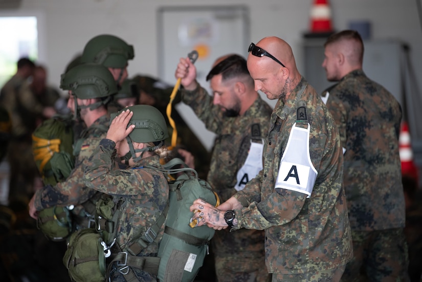 A German jumpmaster checks the parachute of a paratrooper during exercise Air Defender 2023 (AD23) in Saarbrucken, Germany, June 14, 2023. Exercise AD23 integrates both U.S. and allied air-power to defend shared values, while leveraging and strengthening vital partnerships to deter aggression around the world. (U.S. Air National Guard photo by Master Sgt. Phil Speck)