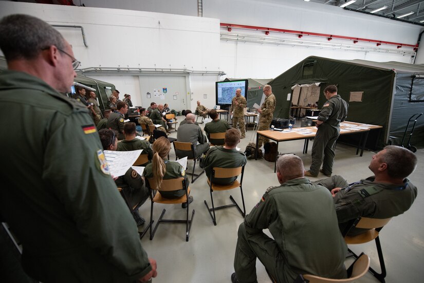 U.S. Air Force Lt. Col. Josh Ketterer, a pilot assigned to the 165th Airlift Squadron, 123rd Airlift Wing, Kentucky National Guard, gives a mission brief to U.S. Air Force, German, and Romanian aircrews at Wunstorf Air Base during exercise Air Defender 2023 (AD23) in Wunstorf, Germany, June 21, 2023. Exercise AD23 integrates both U.S. and allied air-power to defend shared values, while leveraging and strengthening vital partnerships to deter aggression around the world. (U.S. Air National Guard photo by Master Sgt. Phil Speck)U.S. Air Force Lt. Col. Josh Ketterer, a pilot assigned to the 165th Airlift Squadron, 123rd Airlift Wing, Kentucky National Guard, gives a mission brief to U.S. Air Force, German, and Romanian aircrews at Wunstorf Air Base during exercise Air Defender 2023 (AD23) in Wunstorf, Germany, June 21, 2023. Exercise AD23 integrates both U.S. and allied air-power to defend shared values, while leveraging and strengthening vital partnerships to deter aggression around the world. (U.S. Air National Guard photo by Master Sgt. Phil Speck)