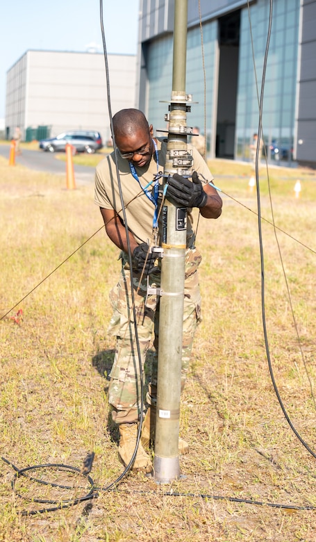 U.S. Air Force Staff Sgt. Anfernee Joseph, expeditionary communications technician with the 146th Contingency Response Flight, 146th Wing, California National Guard, deploys an antenna mast at Wunstorf Air Base, Germany, June 5, 2023, to assist airlift operations in support of exercise Air Defender 2023 (AD23). Exercise AD23 integrates both U.S and allied air-power to defend shared values, while leveraging and strengthening vital partnerships to deter aggression around the world. (U.S. Air National Guard photo by Senior Master Sgt. Vicky Spesard)