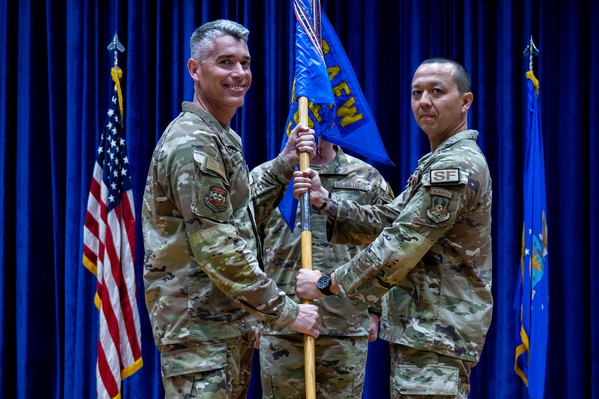 U.S. Air Force Lt. Col. Tito Ruiz, outgoing 386th Expeditionary Security Forces Squadron commander, passes the guidon to Col. George Buch, Jr., 386th Air Expeditionary Wing commander, during a change of command ceremony at Ali Al Salem Air Base, Kuwait, June 23, 2023. Ruiz passed the guidon back to Buch as a symbol of relinquishing command of the unit. (U.S. Air Force photo by Staff Sgt. Kevin Long)