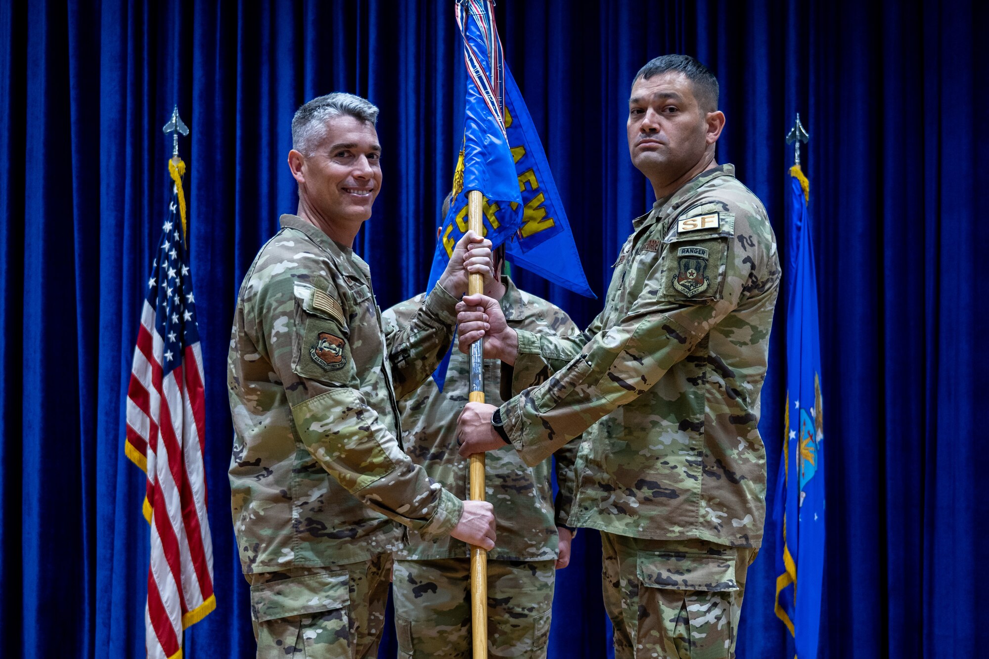U.S. Air Force Col. George Buch, Jr., 386th Air Expeditionary Wing commander, passes the guidon to Lt. Col. Michael E. Wetlesen, incoming 386th Expeditionary Security Forces Squadron commander, during a change of command ceremony at Ali Al Salem Air Base, Kuwait, June 23, 2023. The passing of the guidon symbolizes the passing of command from one commander to the next. (U.S. Air Force photo by Staff Sgt. Kevin Long)
