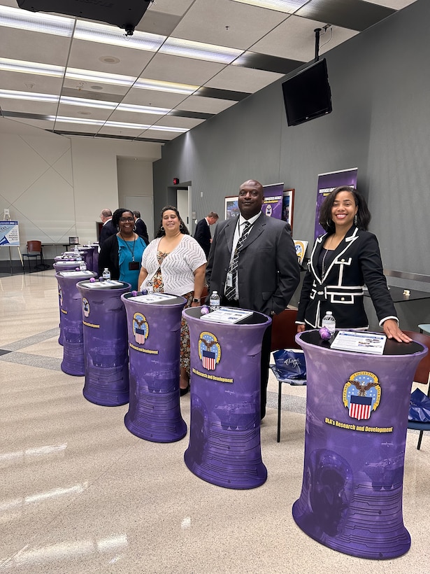 DLA Research and Development project managers standing at their booths during the Snack Symposium.