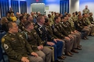 Group of people wearing U.S. Army uniforms sit in an audience.