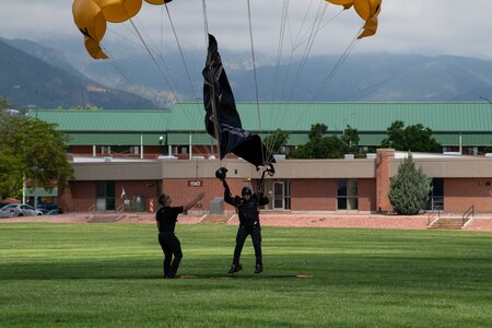 Member of Golden Knights Parachute team lands with Army flag.