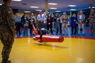 Group of people stand around Army wrestling demonstration.