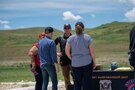 Group of people stand around Army Marksmanship Unit demonstration table.