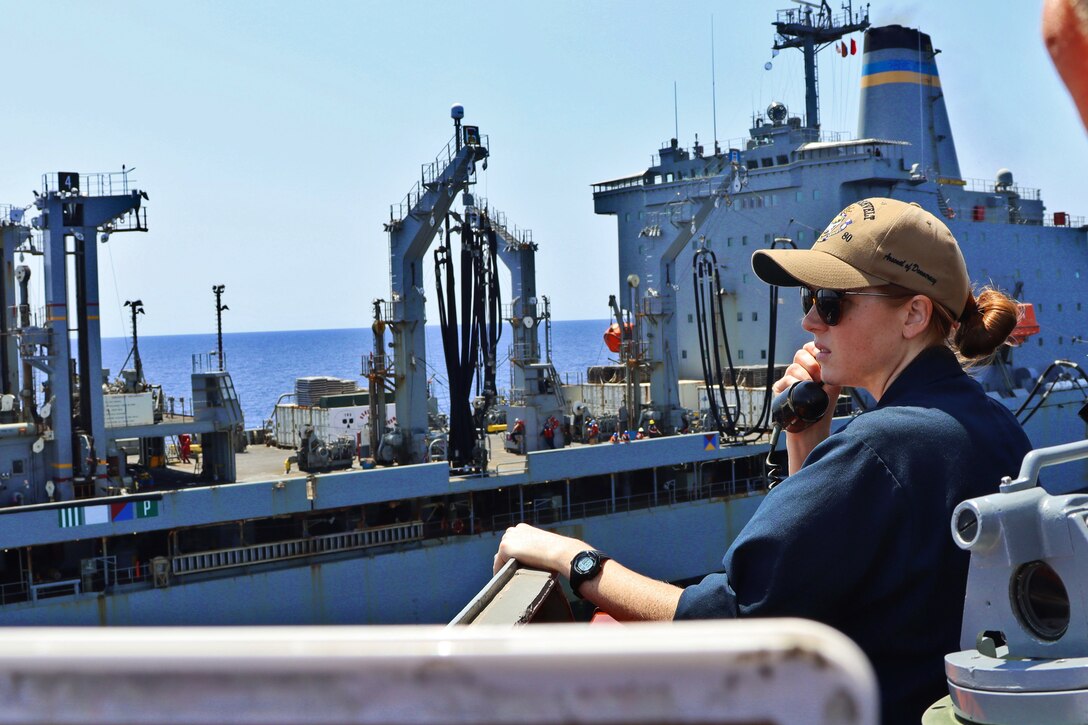 An ensign communicates with a ship during refueling.