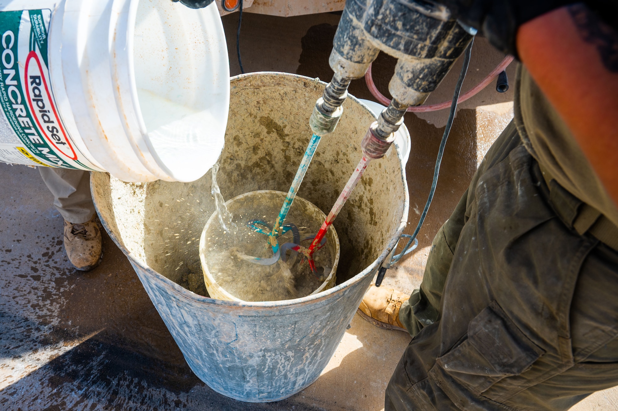 Two men mix up concrete for use on a runway.