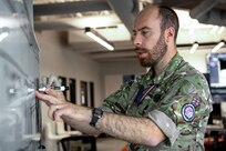 Man in UK military uniform writing on dry erase board with marker