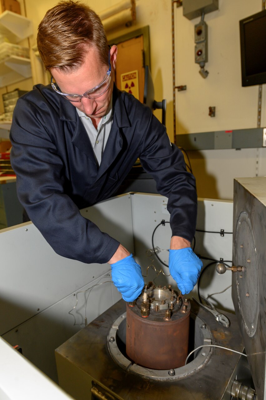Corey Love, Ph.D., materials research engineer at the U.S. Naval Research Laboratory, installs an instrumented canister containing a lithium-ion battery in Washington, D.C., June 19, 2019. This practice is used for failure testing in an accelerating rate calorimeter. (U.S. Navy photo by Sarah Peterson)