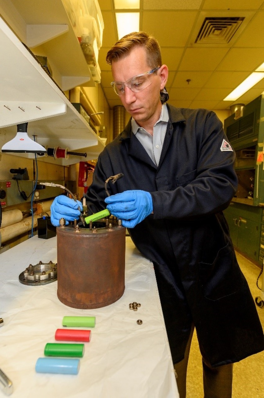 Corey Love, Ph.D., materials research engineer at the U.S. Naval Research Laboratory, places a lithium-ion battery cell in a specially instrumented calorimetry canister in Washington, D.C., June 19, 2019. This practice measures cell voltage and temperature leading up to and during a battery failure experiment. (U.S. Navy photo by Sarah Peterson)