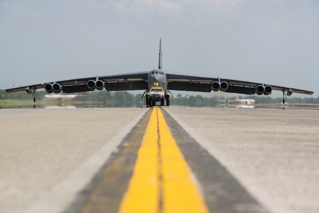 A vehicle drives in front of aircraft down a runway.